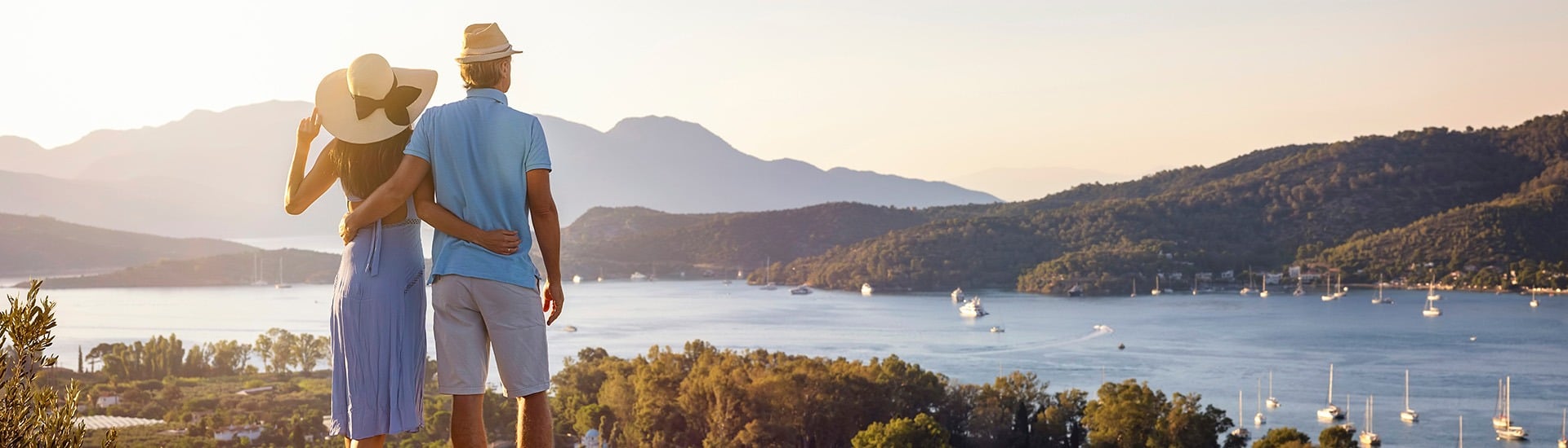 Egy távoli utazáson lévő pár egy befagyott tó partján áll, és egy havas falut néz, magas hegyek között, háttérben az aurora borealis.