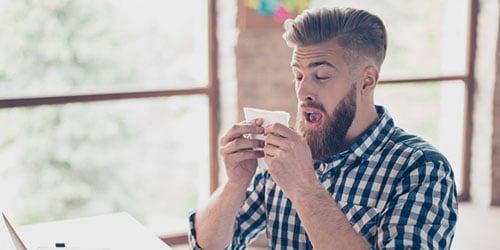 Férfi törött lábbal ül a kanapén és telefonál az utasbiztosítójával