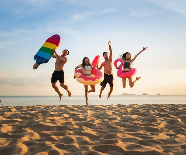 Egy pár nyári vakációján, a medence mellett ülve, pálmafákkal a háttérben – élvezik a pihentető nyaralást utazási biztosítással.