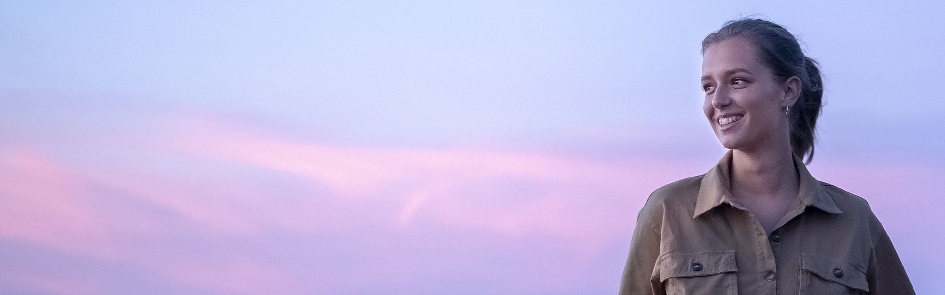 Egy fiatal lány, barátságos, mosolygós arccal, ingben, kiránduláson