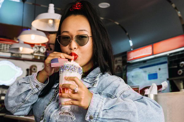 Nő napszemüvegben turmixot tart a kezében és issza