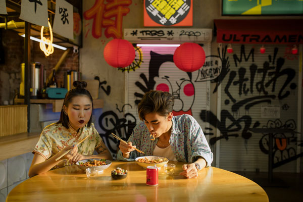 Férfi és nő pálcikával eszik egy japán kis étteremben