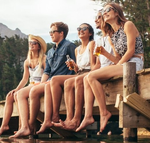 Fiatalok a tóparton egy stégen ülve lóbálják a lábuk