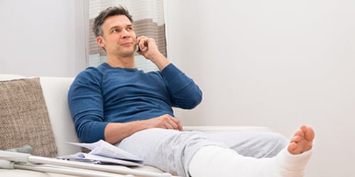 Törött lábú férfi az orvosnál. utazási útlemondási biztosítás.