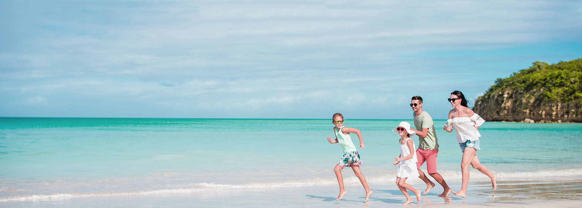 Őrangyal utasbiztosítás - Fiatal család nyaral, boldogan szaladnak a homokos tengerparton a tengerparton
