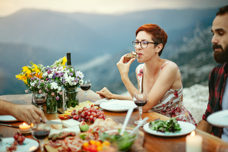 Fiatal nő és férfi egy utazáson baráti társaságban élvezik az olasz ebédet, kilátással