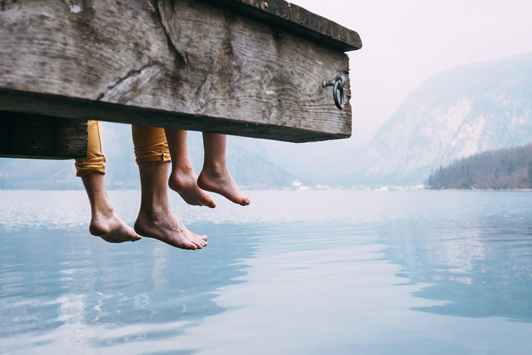 Apa és fial ülnek a stégen egy alpesi tó partján és lógatják a lábukat